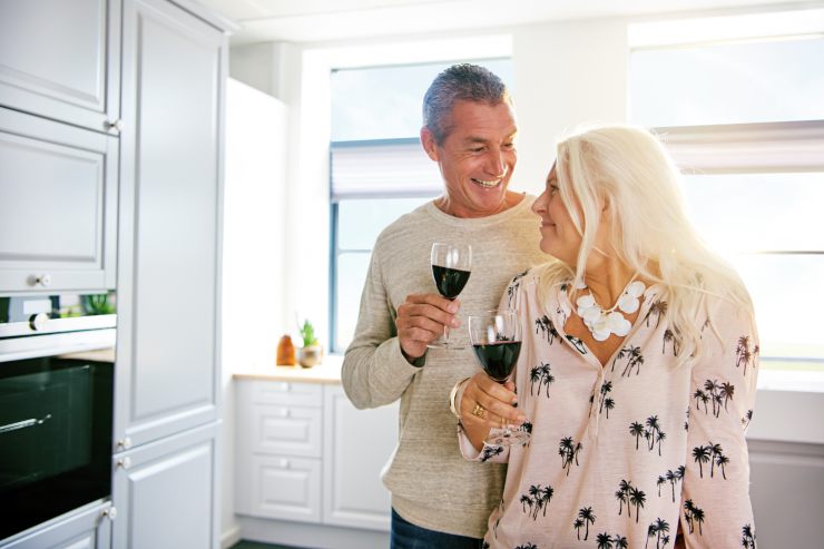 pensionati sorridono con bicchiere di vino in mano
