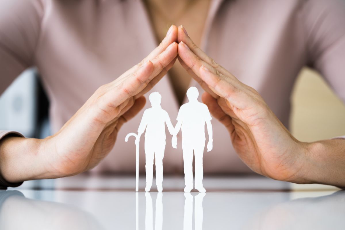Mani che proteggono due figure di pensionati