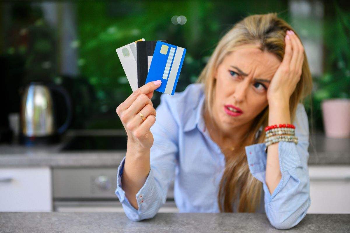persona con debiti che mantiene in mano delle carte di credito