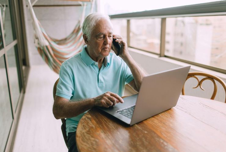 Persona che studia e simula al pc e parlando al telefono la compatilità fra ADI e assegno sociale