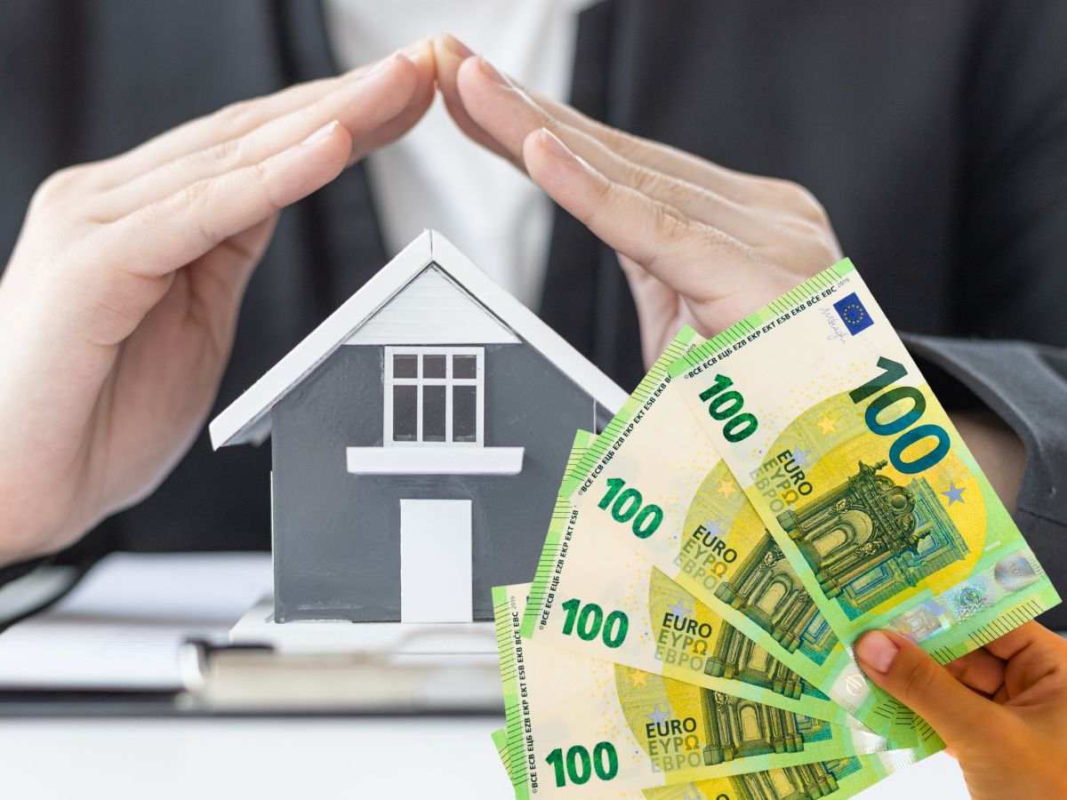 sfondo mani su casetta di legno e banconote 100 euro in mano