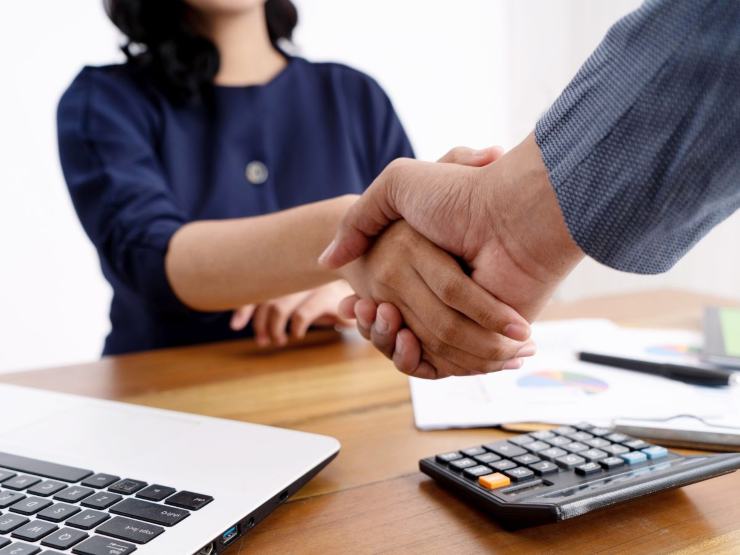 stretta di mano alla scrivania tra due persone con documenti