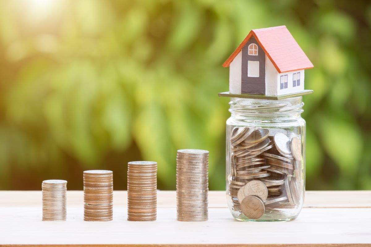 monete, vaso con monete e miniatura casa