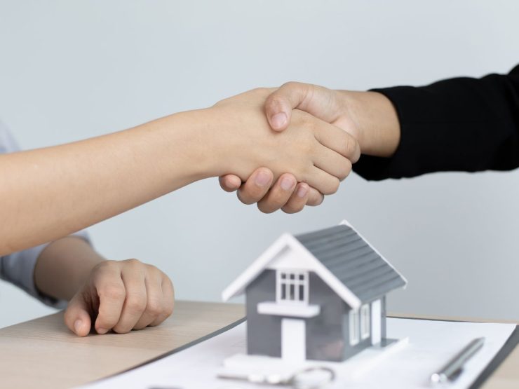mano stretta su casetta in miniatura e contratto
