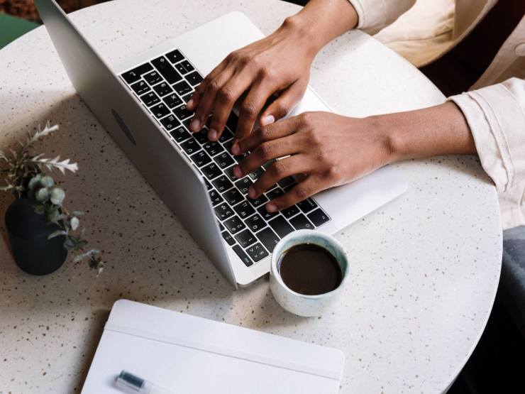 persona al pc con caffè e documenti
