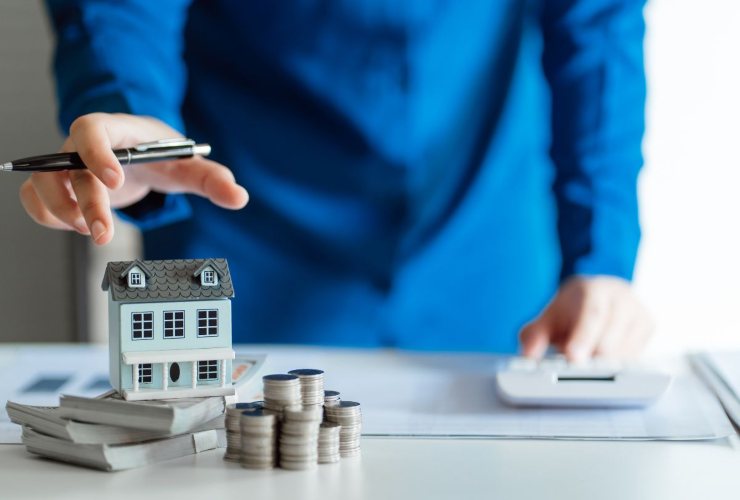minitaura casa e monete e persona che fa dei calcoli sulle spese mutuo e detrazioni